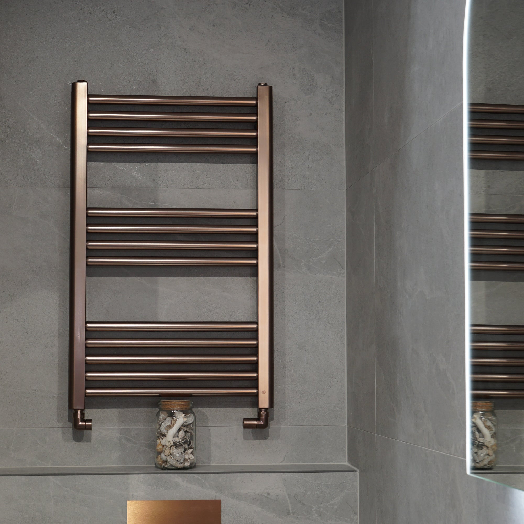 Como Aromawell Heated Towel Rail Brushed Bronze mounted on a grey tiled wall
