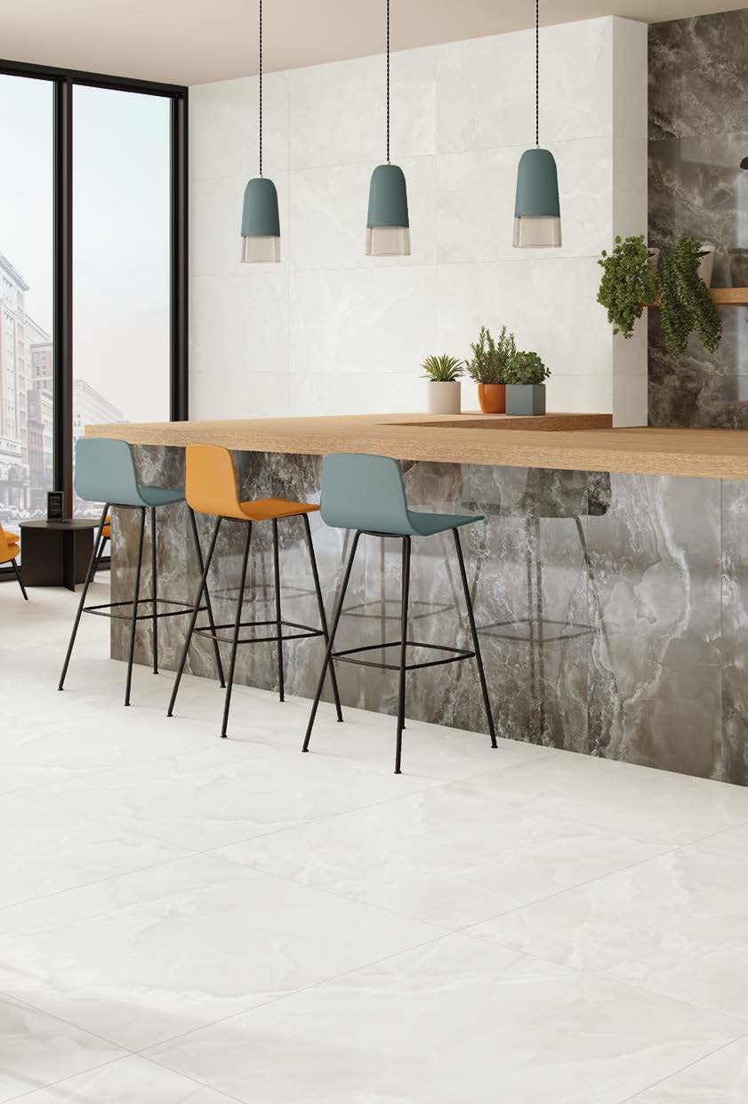 Modern kitchen with a long wooden table and colorful stools against a marble wall.