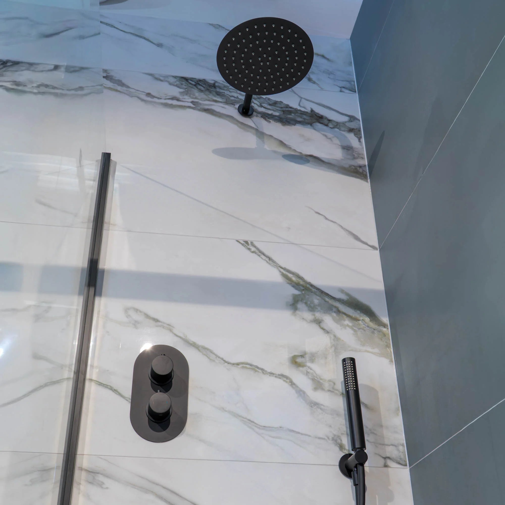 Shower setup with a portofino rain shower head and handheld shower on marble-patterned tiles deluxe bathrooms.