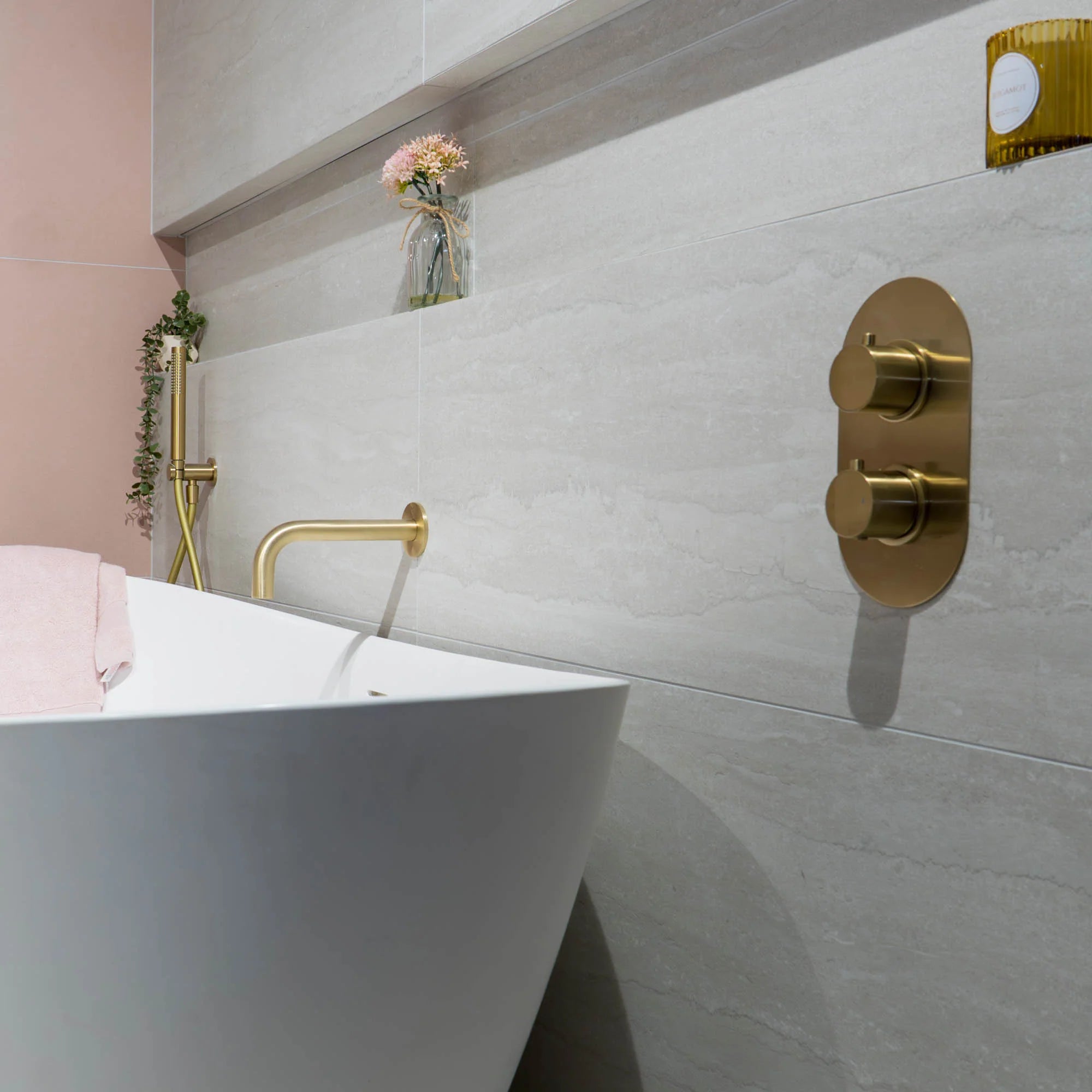 Bathroom setting with a white bathtub, gold faucet, and control panel on a tiled wall deluxe bathrooms