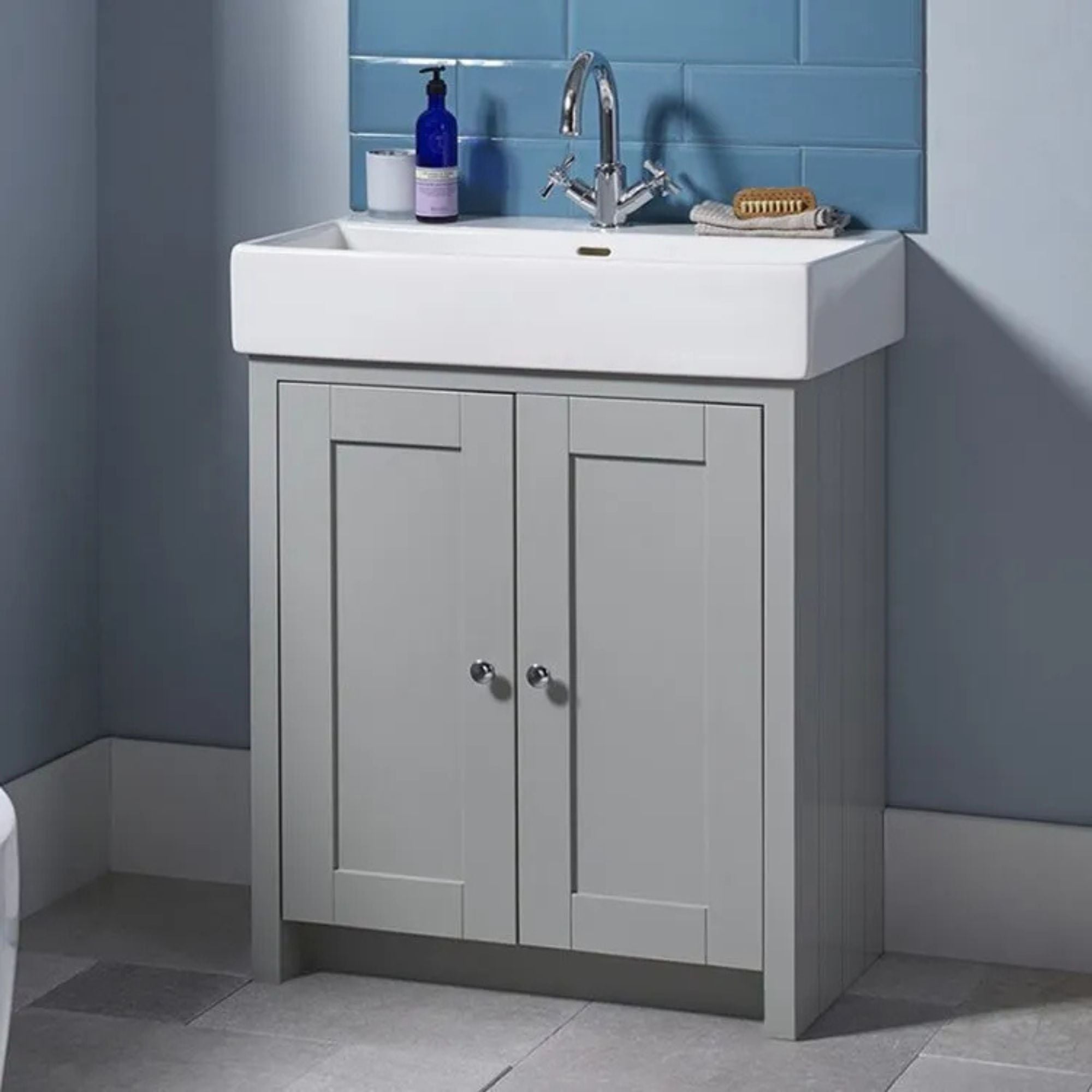 Tavistock lansdown bathroom vanity with white sink and gray cabinets against a blue tiled wall deluxe bathrooms